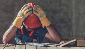 Construction worker stressed over plans at site.