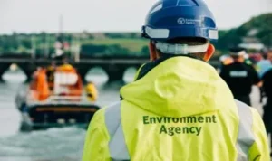 Environment Agency worker by river and rescue boat.