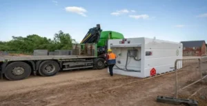 Worker operating fuel container next to lorry on site