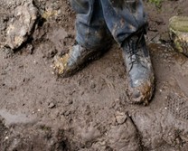 Muddy boots on wet ground outdoors.