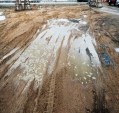 Muddy construction site with standing water puddles.