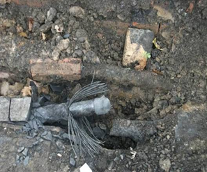 Exposed underground cable amidst dirt and bricks